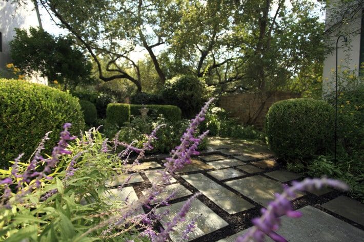 geometric stone porch area with manicured shrubs and flowers