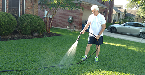 Man hand watering grass in a front yard